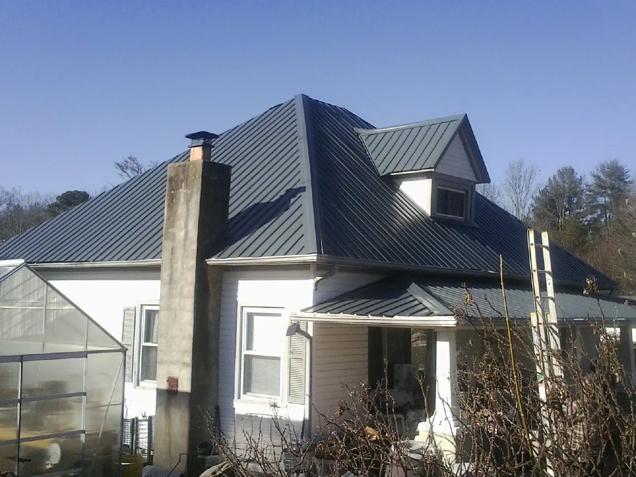Dark blue standing seam metal roof on a white farmhouse with dormer — Slate & Tile Roof Repair by Roofing Brothers in Index