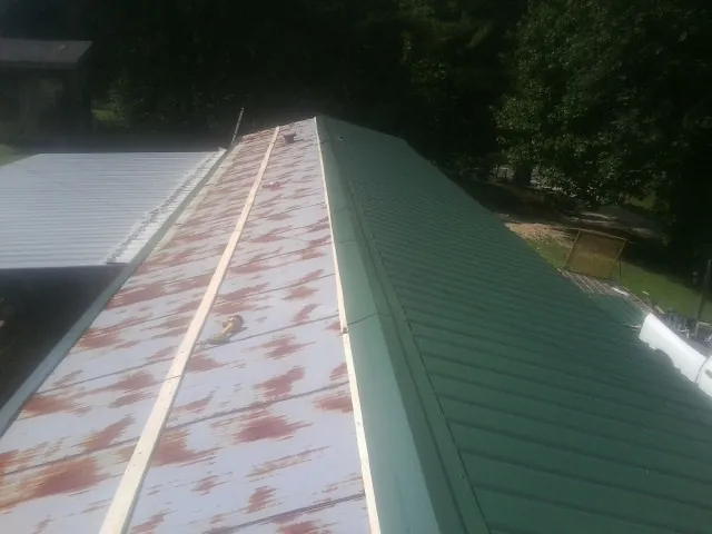 Old rusted panels beside newly installed green metal roofing — Wind Damage Roof Repair by Roofing Brothers in Index