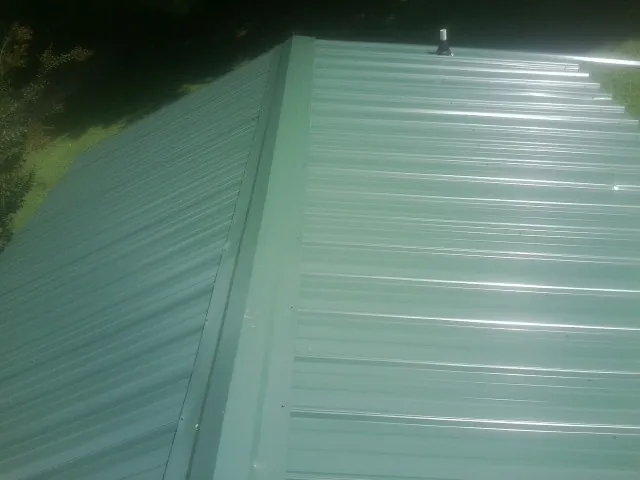 New green metal panels meeting at the ridge of a roof — Flat Roof Repair work by our crew in Index