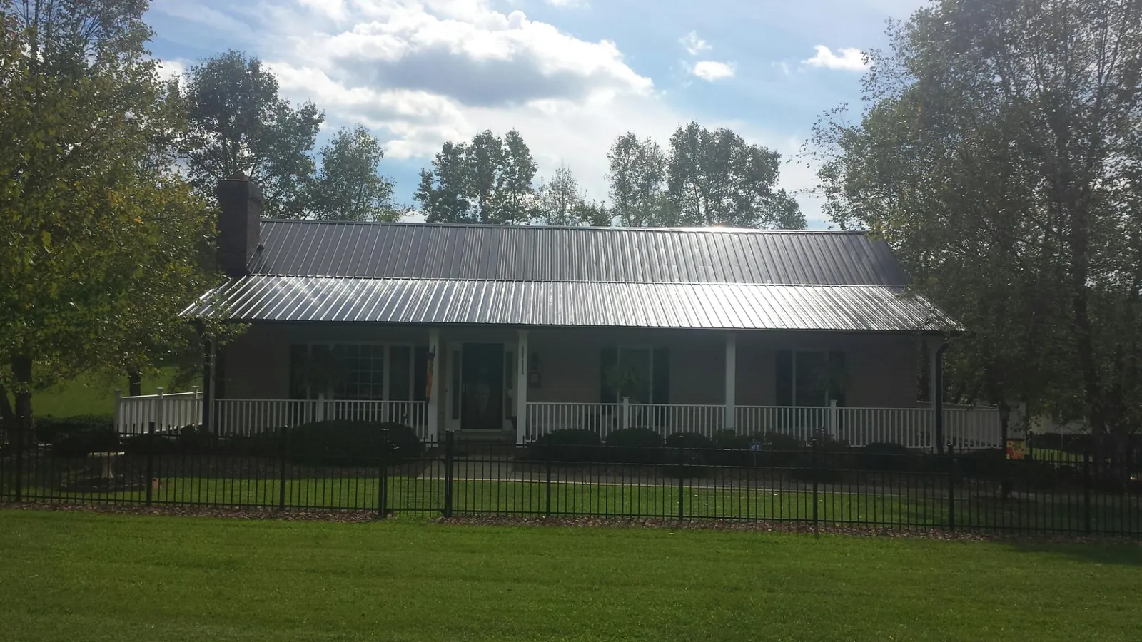 Gray metal roof on a brick ranch with a full width front porch — Gutter Guard Installation work by our crew in Index