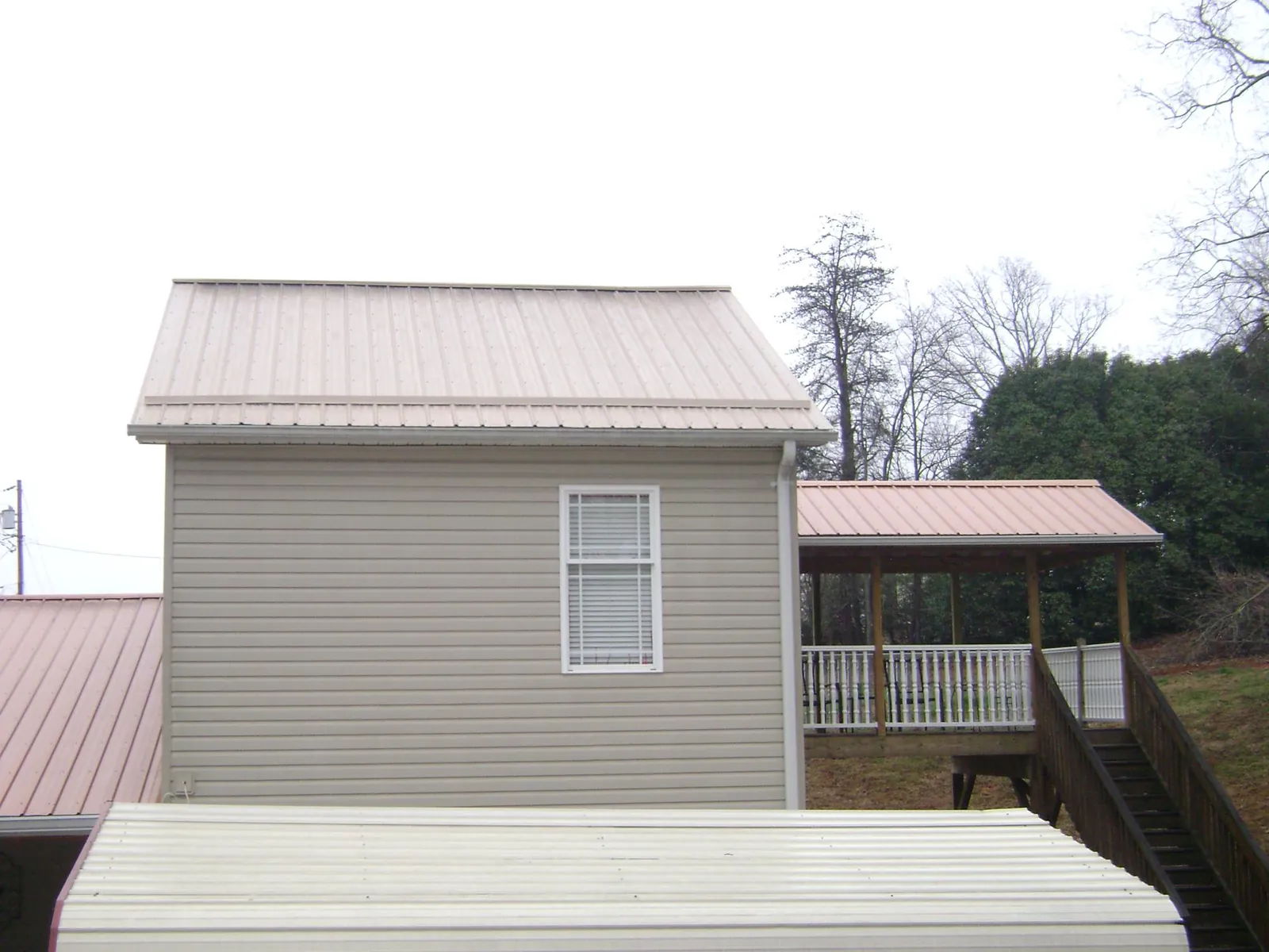 Tan metal roofs on a two story addition and attached porch, from a Roof Replacement job in Index